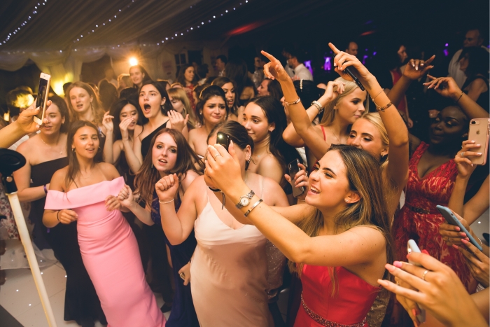 Full dance floor at graduation party, guest taking photos