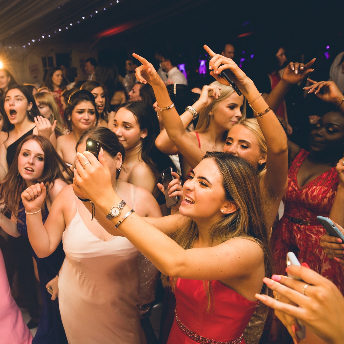 Full dance floor at graduation party, guest taking photos